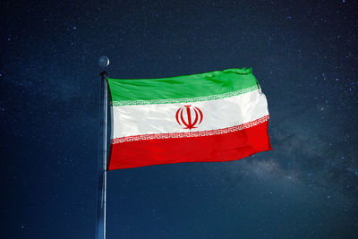 Low angle view of iranian flag against star field sky