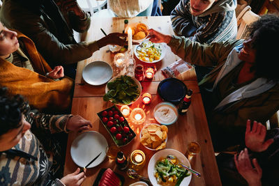 High angle view of friends enjoying food and drink while sitting in log cabin