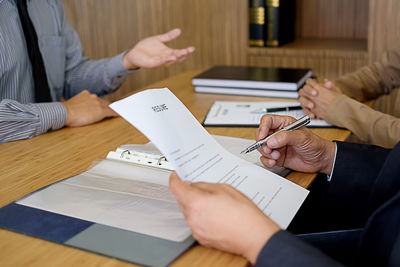 Midsection of business people interviewing candidate on desk