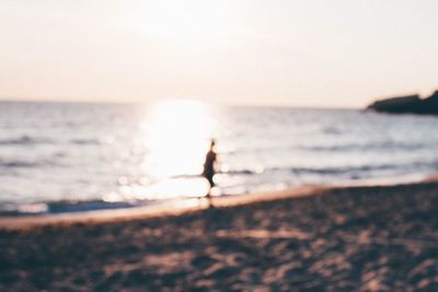 Silhouette man on beach against sky during sunset