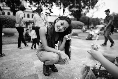 Full length portrait of woman crouching outdoors