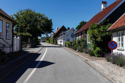 Road amidst trees and buildings against sky