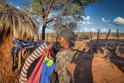 Woman standing on field by trees against sky