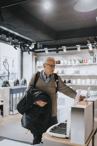 Senior man examining appliance while shopping in appliances store