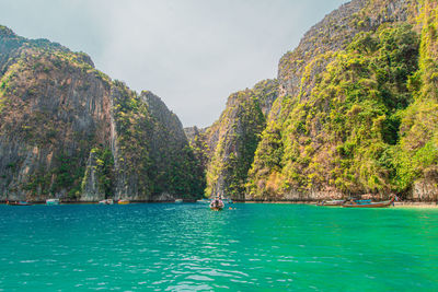 Scenic view of sea by mountain against sky