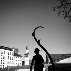 Woman walking on city street against clear sky