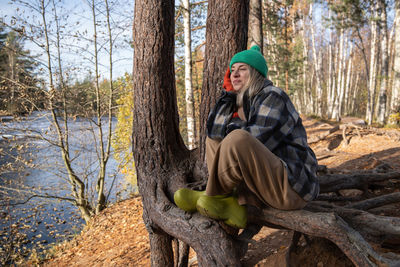 Portrait of man sitting on tree trunk