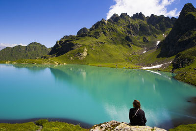 Rear view of man looking at lake against mountain