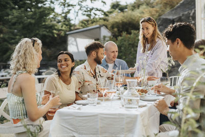 Happy male and female friends enjoying food while celebrating dinner party at cafe