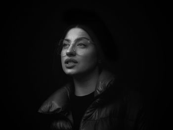 Portrait of young woman against black background