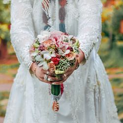 Midsection of a bride holding flower bouquet