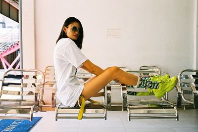 Portrait of woman sitting on chair against wall