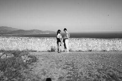 Man and woman standing on shore against sky