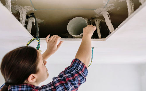 Woman placing tube for kitchen hood installation