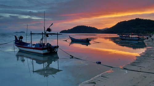 Boats moored on sea against sky during sunset