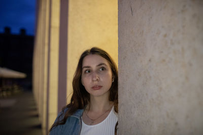 Young woman looking away against wall