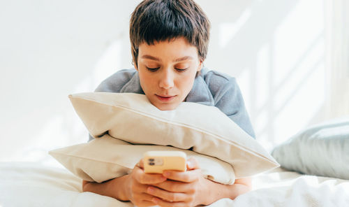 Young carefree woman lying on the bed browsing social networks in her mobile phone. banner