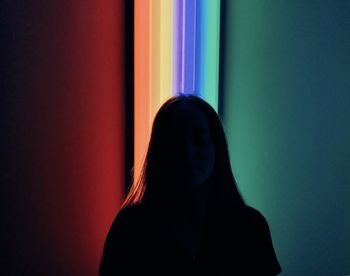 Portrait of silhouette woman standing against colored background