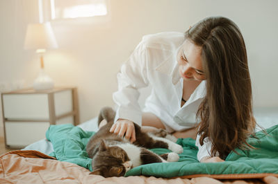 Woman with cat on bed at home