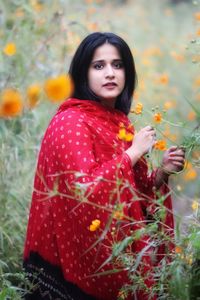 Portrait of smiling woman standing against red plants