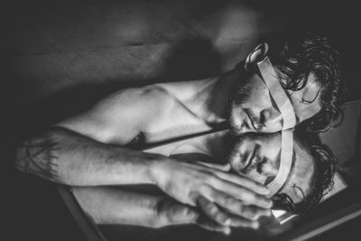 Man with adhesive tape covering eyes by mirror on table