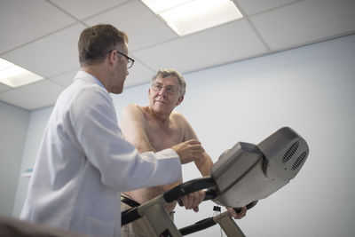 Doctor talking to senior patient on treadmill