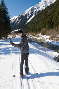 Full length portrait of teenage boy enjoying cross-country skiing in alps