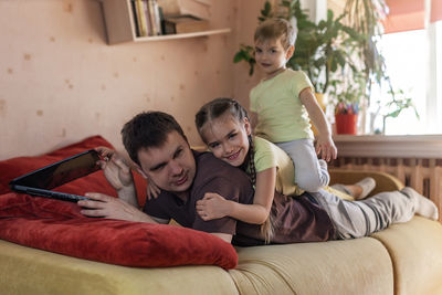 Rear view of mother and daughter on sofa at home