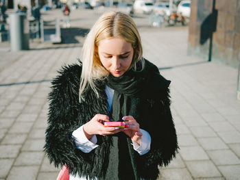 Young woman using mobile phone in city