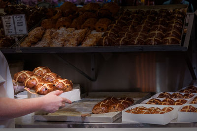 Cropped image of person holding hot cross buns in bakery