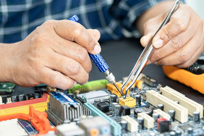 Midsection of engineer repairing mother board