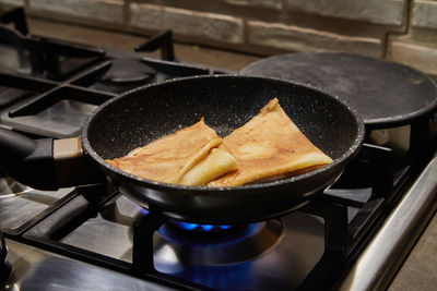 Chef pan-frying crepe suzette pancakes with cognac and citrus sauce