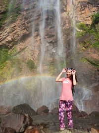 Woman standing on rock against waterfall