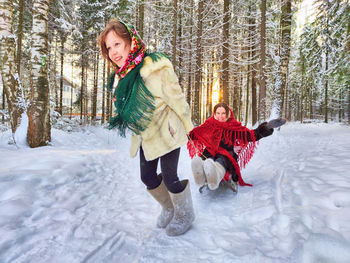 Portrait of young woman standing on snow covered field