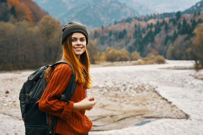 Portrait of smiling young woman standing against mountain