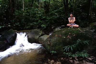 Full length of man on rock in forest