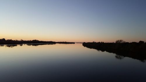 Scenic view of lake against clear sky during sunset