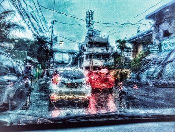 Cars on road seen through wet glass window