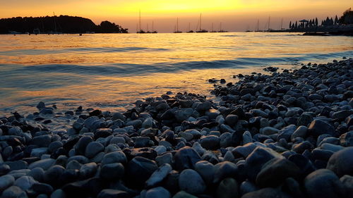 Rocks on beach against sky during sunset