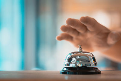 Close-up of hand holding clock on table