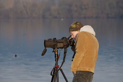 Side view of man photographing against sky