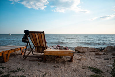 Deck chairs on beach against sky