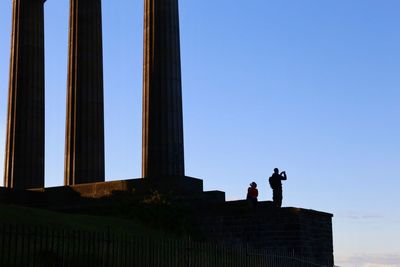 Low angle view of men against clear blue sky