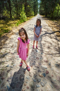 High angle view of sisters standing on footpath in forest