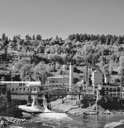 Buildings by river against clear sky