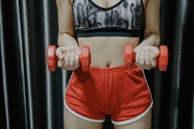 Midsection of woman exercising with dumbbells