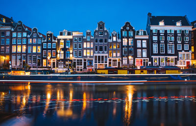 Reflection of illuminated buildings in river at dusk