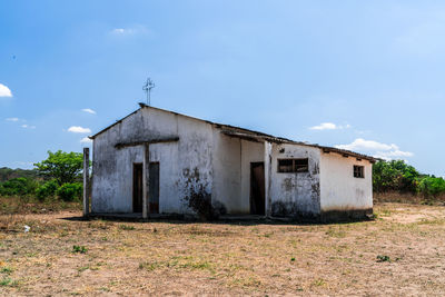 Abandoned house on field against sky