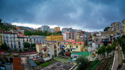 Naples neighborhood with yellow and red colored blocks seen from above and a dramatic cloudy sky