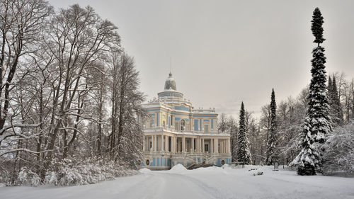 Snow covered land and trees by building against sky